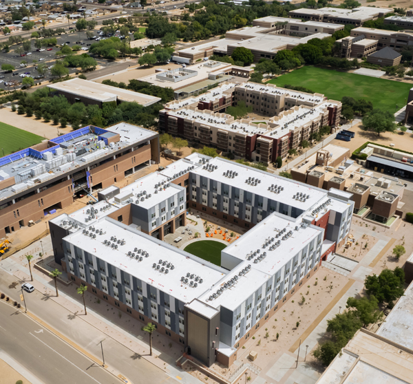 Aerial view of ASU West Valley campus with a large U-shaped building in the foreground and various other structures and a green field in the background.